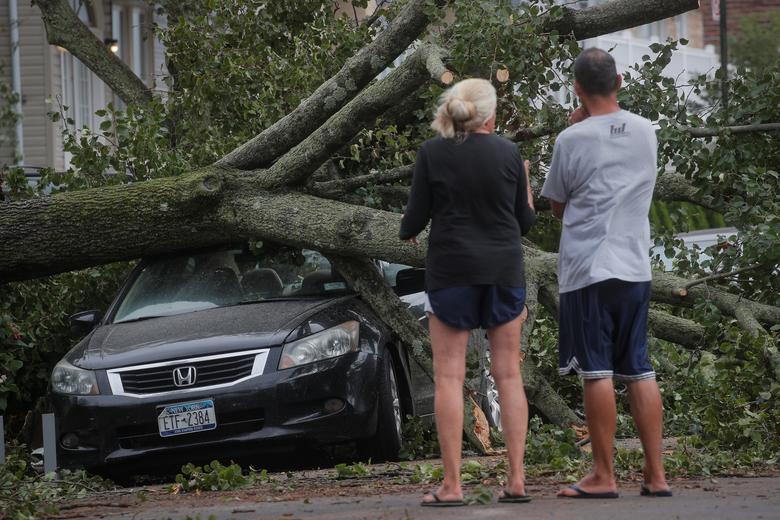 Ngày 4/8, bão đã quét qua các bang: New York, New Jersey và Connecticut... khiến ít nhất 4 người thiệt mạng và khoảng 2,7 triệu người rơi vào cảnh mất điện. Trong ảnh, một chiếc xe ô tô bị một cây lớn đổ ngã tại khu vực Rockaway của thành phố New York đè bẹp 