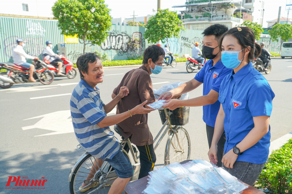 Hai người dân đi đường rất vui mừng và bất ngờ khi nhận được khẩu trang từ các bạn Đoàn viên tại điểm phát khẩu trang trước trụ sở Báo Phụ nữ TPHCM.