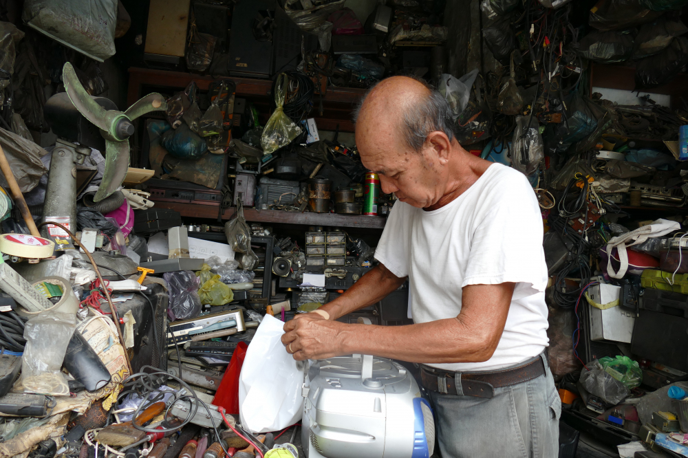 Cửa tiệm sửa đồ cổ của ông Nguyễn Minh Trí cách chợ Thủ Đức khoảng 800m, nằm đối diện với ngã ba Chương Dương - Võ Văn Ngân, quận Thủ Đức