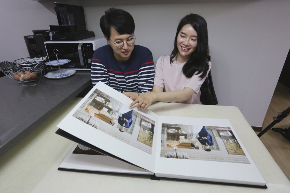 Vợ Triều Tiên Kim Seo-yun và chồng Hàn Quốc Lee Jeong-sup đang xem lại ảnh cưới tại nhà ở Seoul - Ảnh: AP