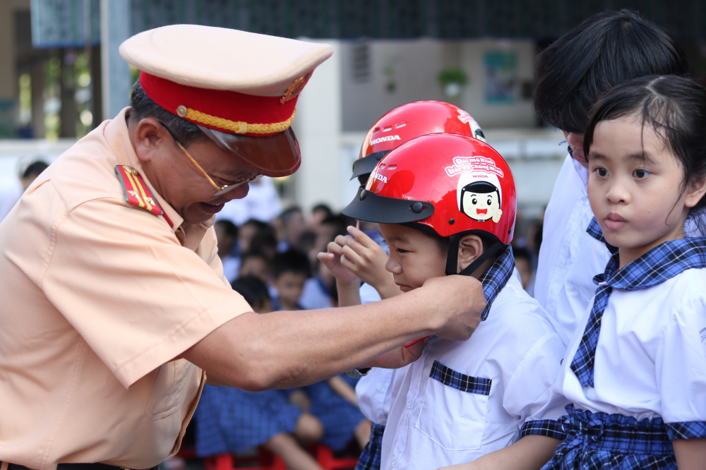 Trung tá Phạm Văn Tuyến - Phó đội trưởng Đội Cảnh sát giao thông Cát Lái - trao tặng mũ bảo hiểm cho các em., 