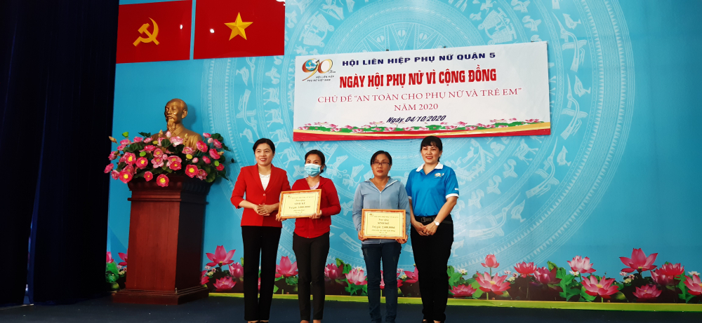 Bà Nguyễn Trần Phượng Trân (trái) và bà Nguyễn Thị Ánh Loan (phó chủ tịch Hội LHPN Q.5 (phải) trao bảng tượng trưng phương tiện làm ăn cho hai phụ nữ có hoàn cảnh khó khăn. 