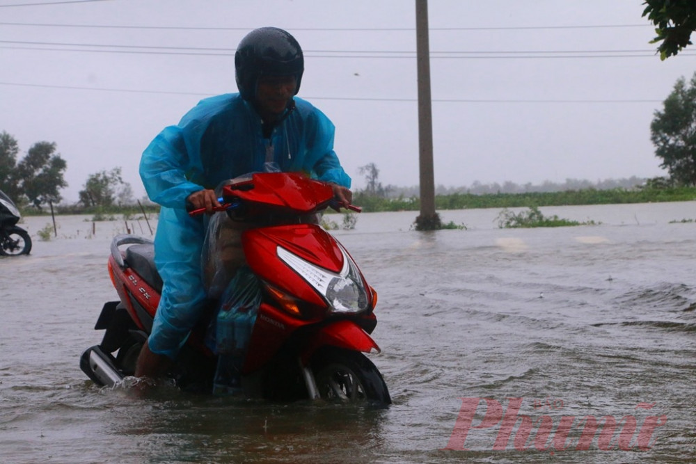 Một người dân cố vượt qua một đoạn đường ngập lụt