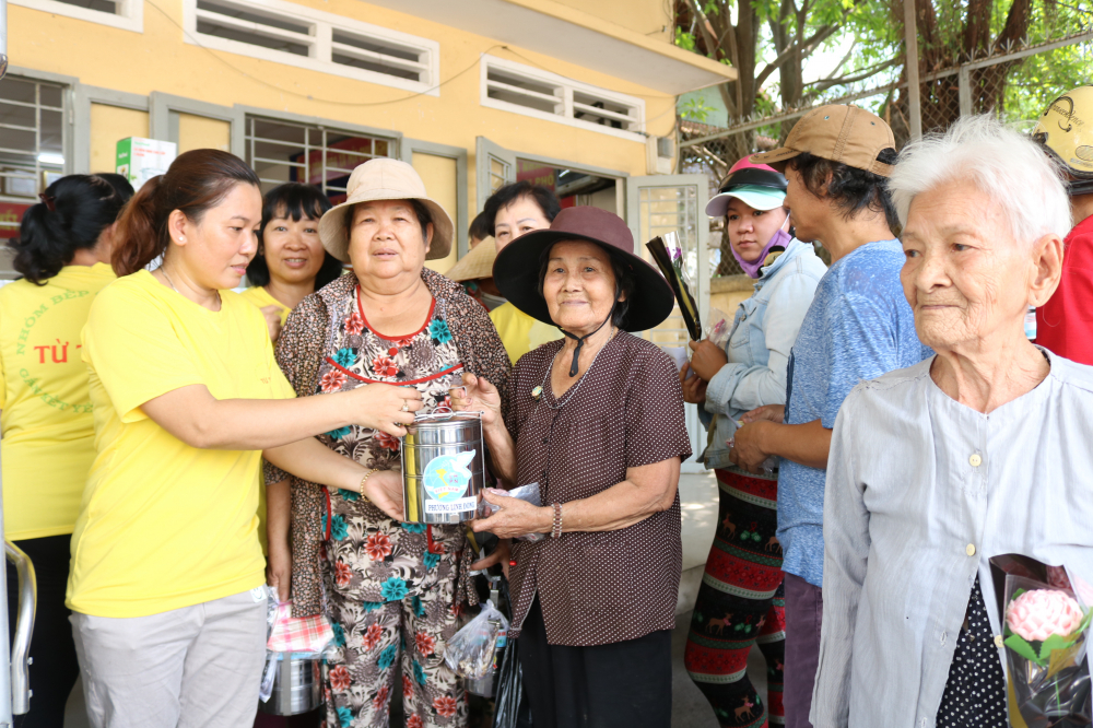 Chị Trần Thanh Dung (bìa trái) trao tặng cơm và cà men inox cho bà con. 