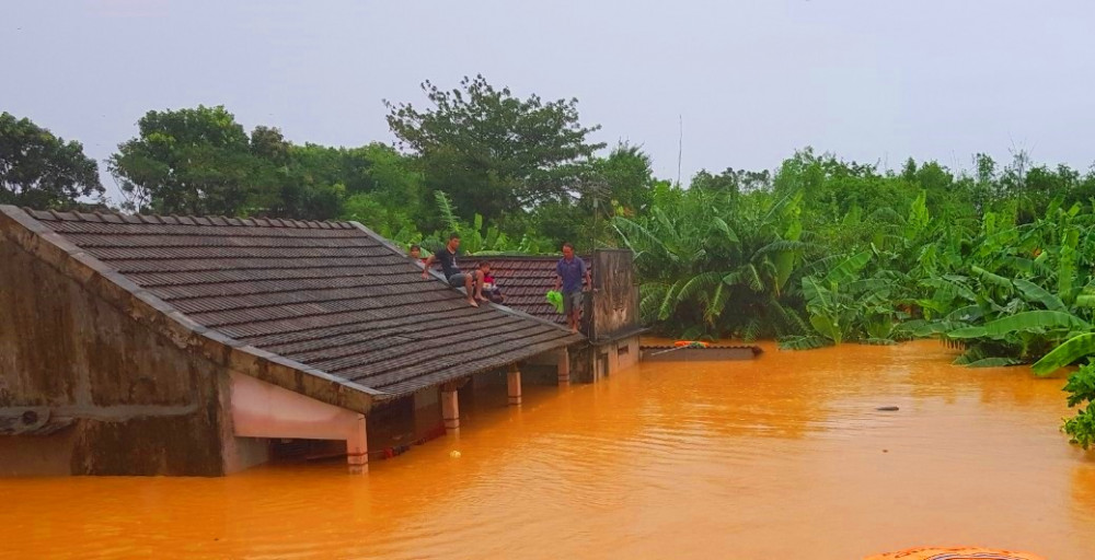 Nước lũ dâng cao, người dân leo trên mái nhà để chờ đội cứu hộ