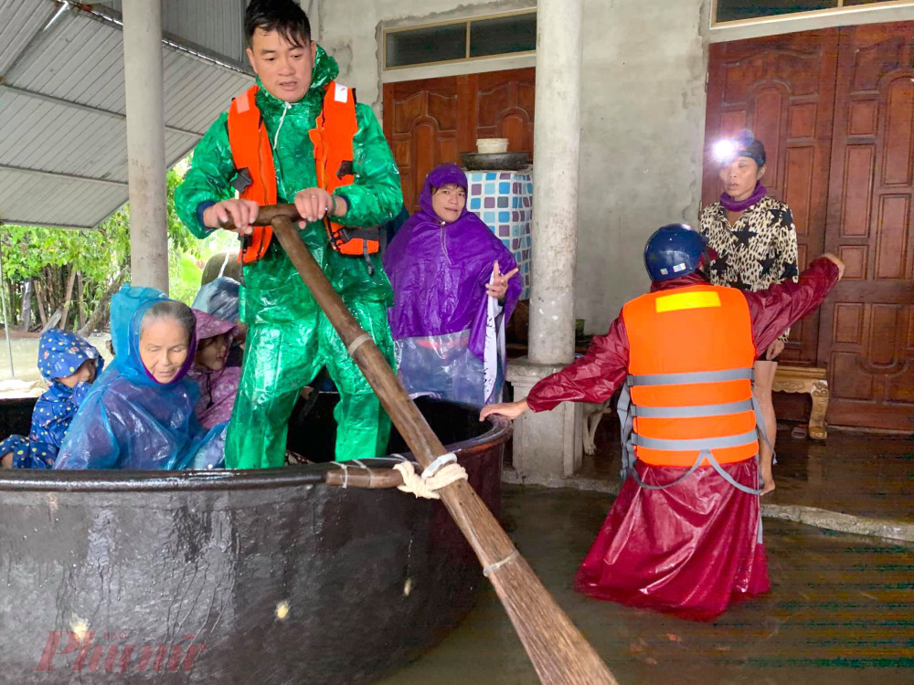 Lực lượng chức năng sử dụng thuyền thúng di dời người dân ra khỏi khu vực ngập sâu