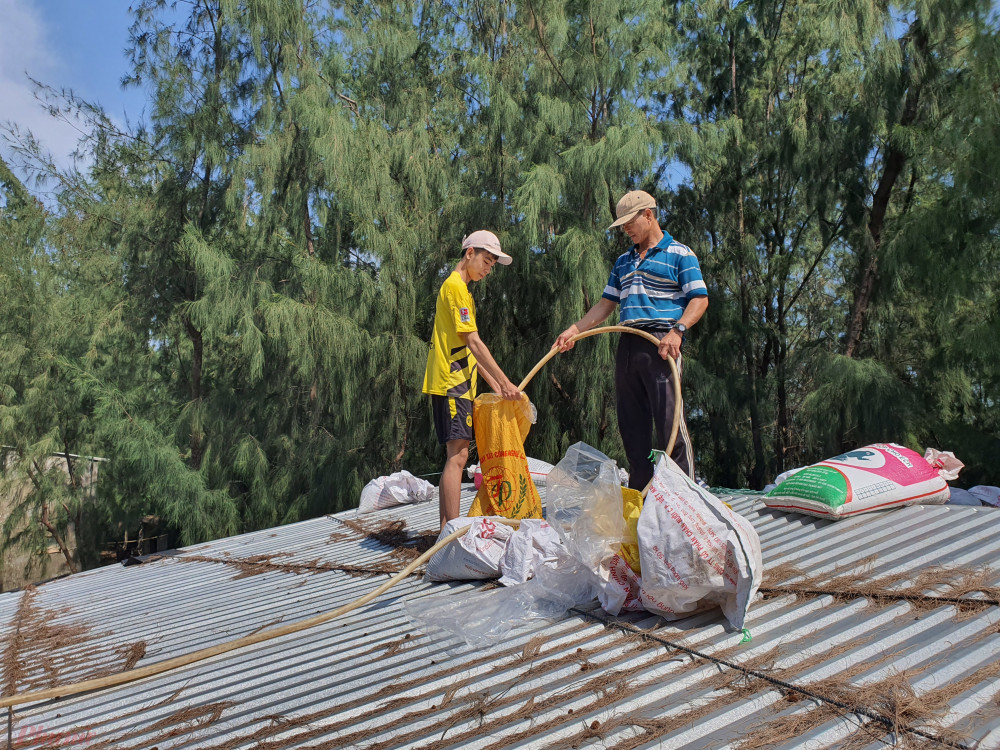 Thay vì dùng bao cát, người dân miền Trung đang dùng túi nilon đưa lên mái nhà rồi đổ nước vào đề chằng mái nhà, vừa tiết kiệm sức vừa không phải đi đào cát