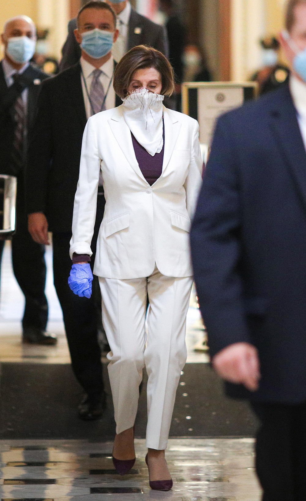 Suit trắng kèm khăn che đồng điệu được bà kết hợp áo thun và giày nâu ánh tím.