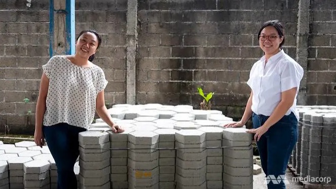 Hai người sáng lập Rebricks là Ovy Sabrina (trái) và Tan Novita đứng trước một chồng gạch chứa nhựa tái chế nhiều lớp tại nhà máy của họ ở Jakarta.