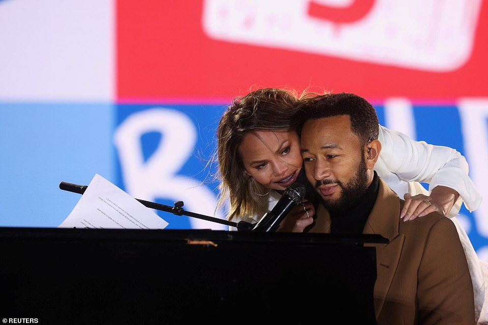 Chrissy Teigen (trái) dựa vào chồng cô John Legend (phải) ở Philadelphia khi anh biểu diễn tại một cuộc vận động tranh cử do ứng cử viên phó tổng thống của đảng Dân chủ Kamala Harris tổ chức.