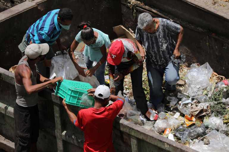 Tìm kiếm thức ăn trong các xe rác ở Caracas, Venezuela - Ảnh: Reuters