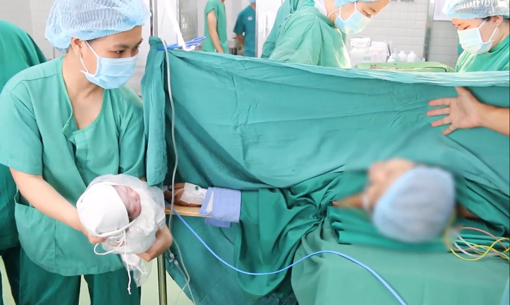 Bác sĩ phẫu thuật bắt con cho chị H. thành công, chị vui mừng nhìn thấy con trai chào đời, ảnh cắt từ clip