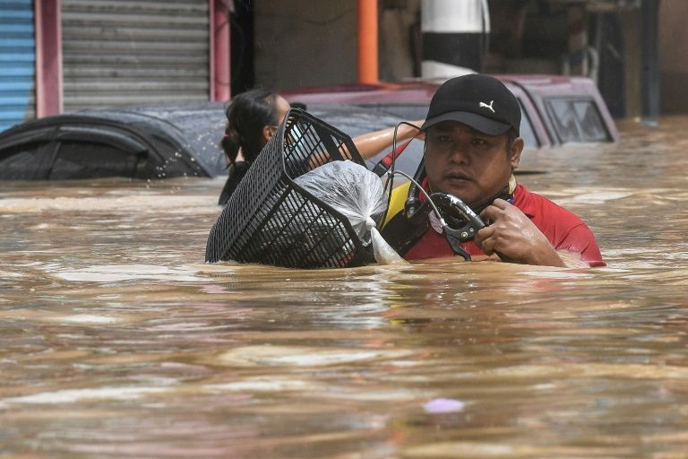 Người dân ngoại ô Manila di chuyển trong nước lụt - Ảnh: Getty Images