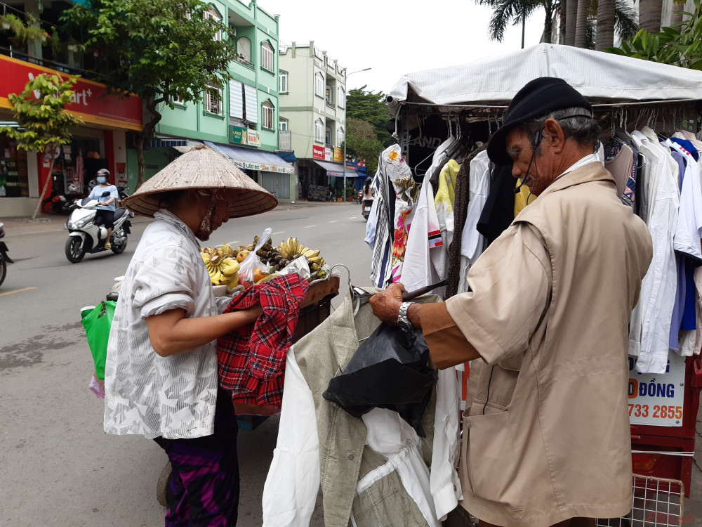 Người phụ nữ bán hàng rong hồ hởi chọn cho mình một chiếc áo phù hợp