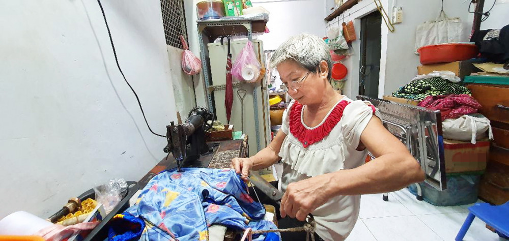 Bà Muối  sửa quần áo cho khách để kiếm tiền đi chợ