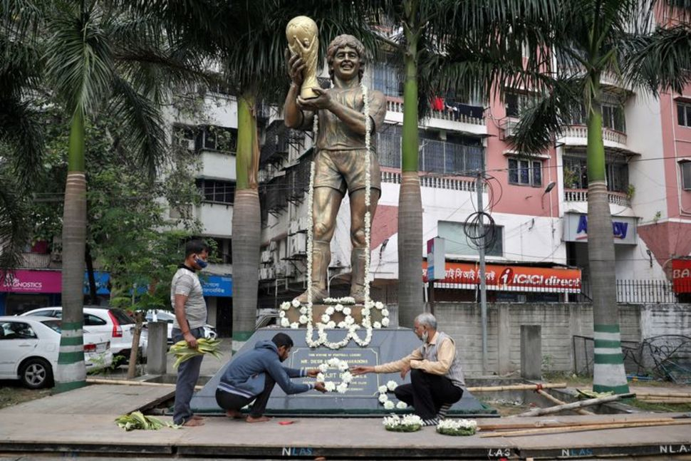 Người dân trang trí bức tượng Diego Maradona – cầu thủ vĩ đại của bóng đá Argentina trước một buổi cầu nguyện, ở Kolkata, Ấn Độ.