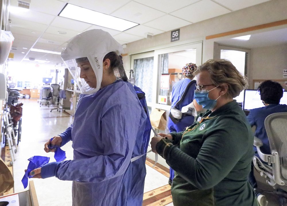 Deb Dalsing, quản lý y tá của đơn vị điều trị COVID-19 tại UW Health hỗ trợ y tá Ainsley Billesbach mặc thiết bị bảo vệ cá nhân tại bệnh viện ở Madison, Wisconsin.