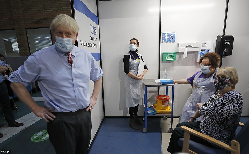 Thủ tướng Anh Boris Johnson trò chuyện cùng bà Lyn Wheeler trước khi bà tiêm vắc-xin tại cơ sở y tế ở London