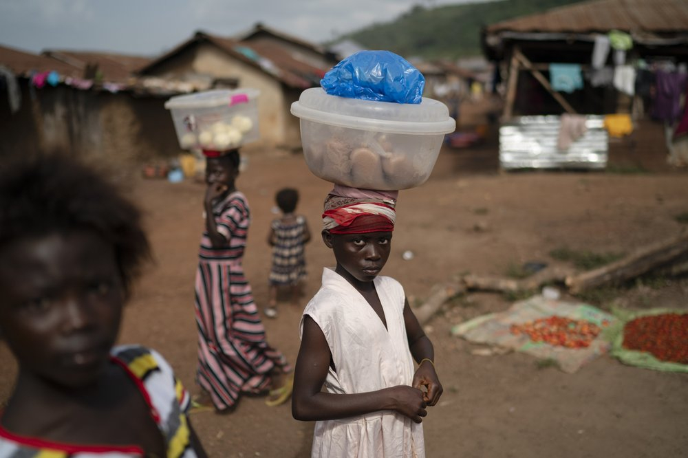 Isatu, 12 tuổi, mang trên đầu những gói bột gạo để bán tại làng Komao, ngoại ô Koidu, huyện Kono, Sierra Leone. Sierra Leone đóng cửa biên giới trước khi đất nước có ca nhiễm COVID-19 đầu tiên, kết quả là cả nước chỉ ghi nhận 2.434 ca nhiễm và 74 trường hợp tử vong - Ảnh: AP