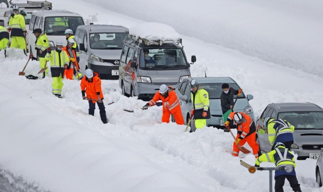 Các nhân viên cứu hộ và Lực lượng phòng vệ mặt đất hỗ trợ dọn tuyết trên đường cao tốc.