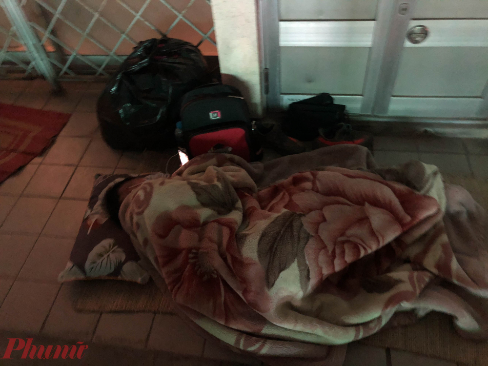 Một người đi chăm sóc người bệnh đã chuẩn bị sẵn chăn chiếu để ngủ qua đêm trên nền gạch. 