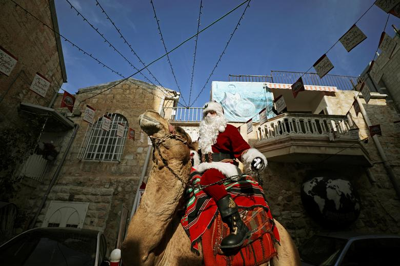 Ông già Noel cưỡi lạc đà phát cây thông Noel cho người dân ở Thành phố cổ Jerusalem, Israel