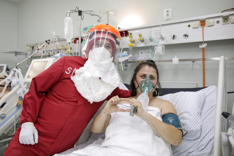 Ionut Ivan, một y tá 40 tuổi, mặc bộ đồ bảo hộ màu đỏ, đội mũ đỏ và đeo bộ râu trắng để tạo dáng chụp ảnh bên cạnh Brindusa Gheorghiu, một bệnh nhân mắc COVID-19, tại phòng chăm sóc tích cực ICU của Bệnh viện phổi Marius Nasta, ở Bucharest, Romania