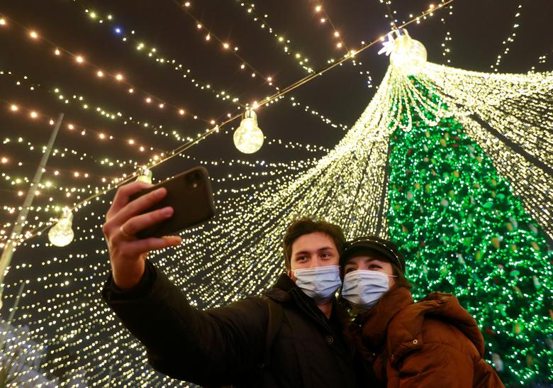 Một cặp đôi đeo khẩu trang chụp ảnh tự sướng trước cây thông Noel ở trung tâm Kyiv, Ukraine