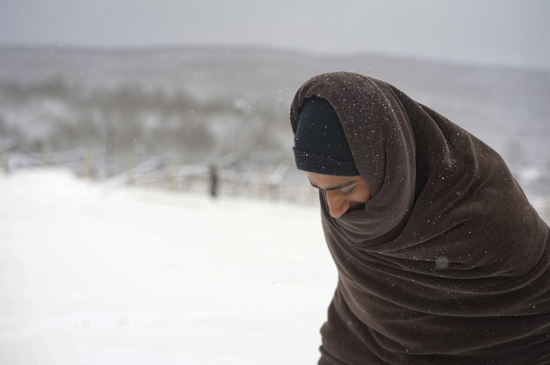 Một người di cư đi quấn chăn đi trong tuyết trắng tại trại Lipa, tây bắc Bosnia, gần biên giới với Croatia - Ảnh: AP