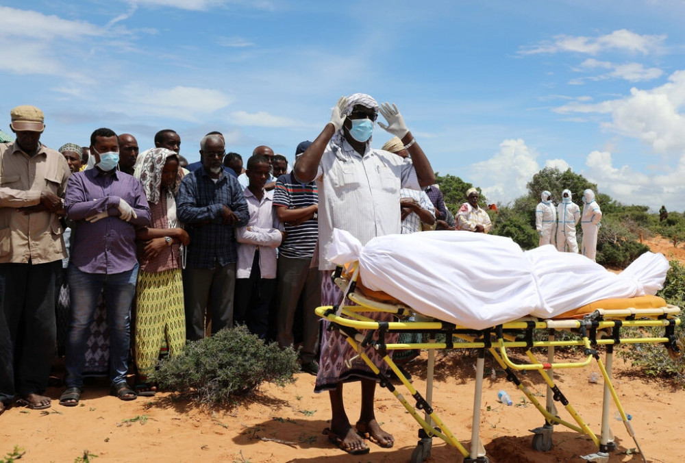 Những người đưa tang cầu nguyện trước thi thể của một người đàn ông bị nghi nhiễm COVID-19, tại ngoại ô Mogadishu, Somalia