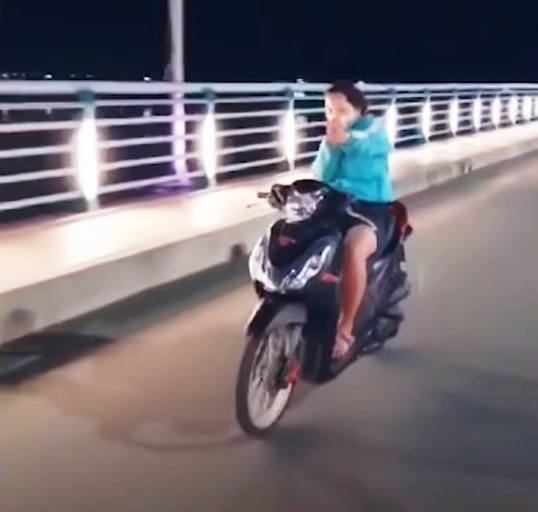 Cô gái trẻ vừa lái xe máy vừa thả tay để múa may