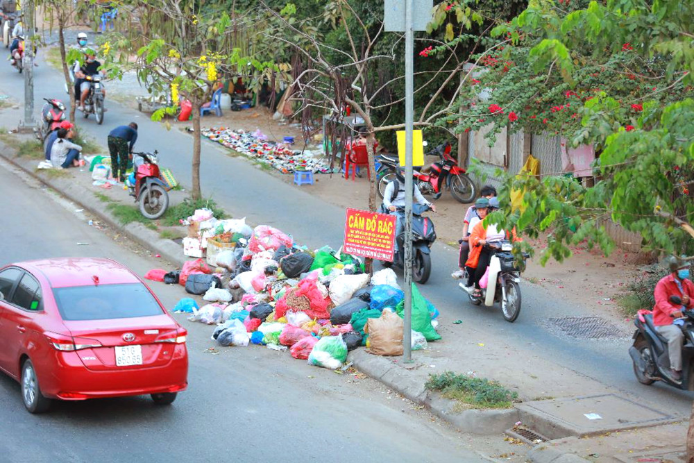 Một đống rác ngay trên vỉa hè với tấm bảng “cấm đổ rác”