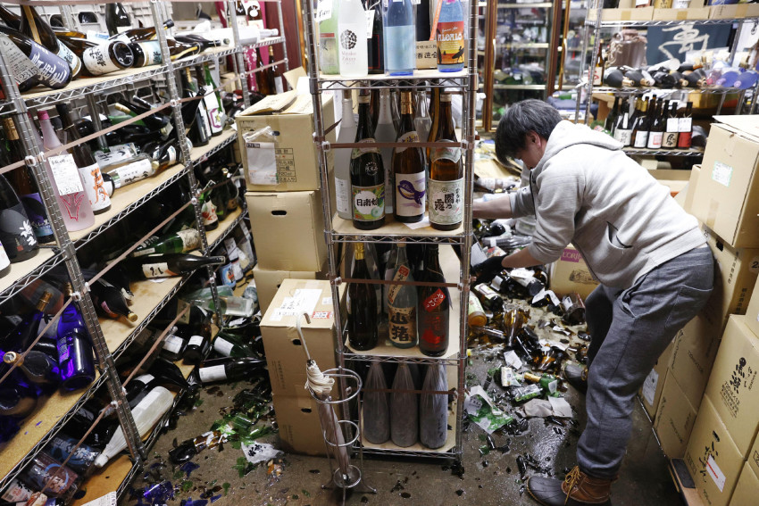Người quản lý của một cửa hàng rượu thu dọn những chai rượu vỡ ở thành phố Fukushima vào tối thứ Bảy, sau trận động đất mạnh với cường độ sơ bộ là 7,1 làm rung chuyển vùng đông bắc Nhật Bản