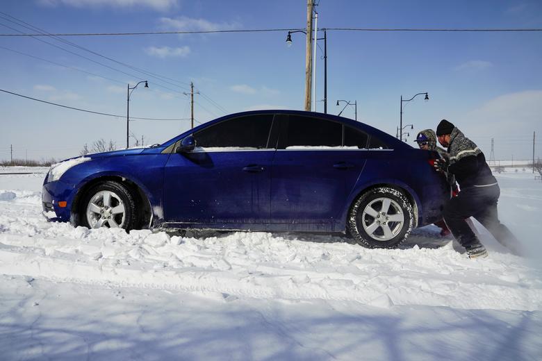 Hai người đàn ông đang cố 'giải cứu' chiếc xe hơi bị mắc kẹt trong đống tuyết dày cộm ở thành phố Oklahoma, bang Oklahoma hôm 15/2.