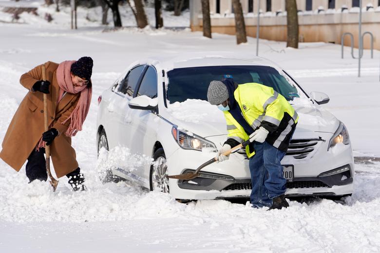 Quincy Perkins (phải) đang giúp một người phụ nữ đào tuyết để chiếc xe có thể di chuyển.