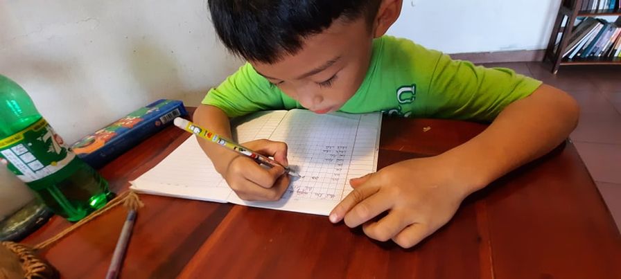 Bé Cao Khải, học sinh lớp 1 trường tiểu học An Phong đang tập viết chữ.