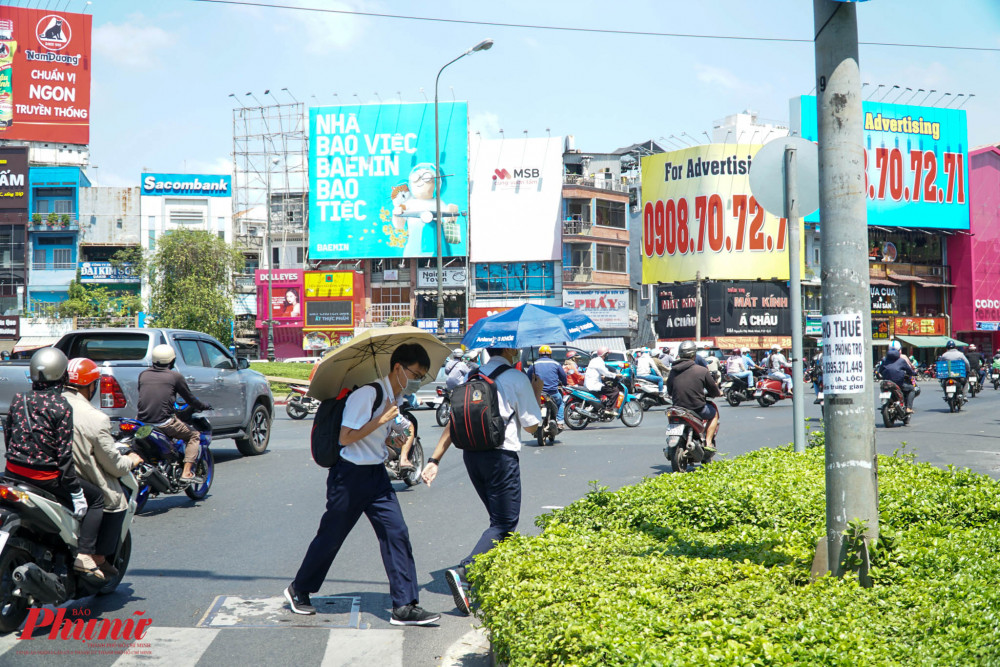 Quá nắng, nhiều học sinh phải dùng dù che nắng khi di chuyển trên đường