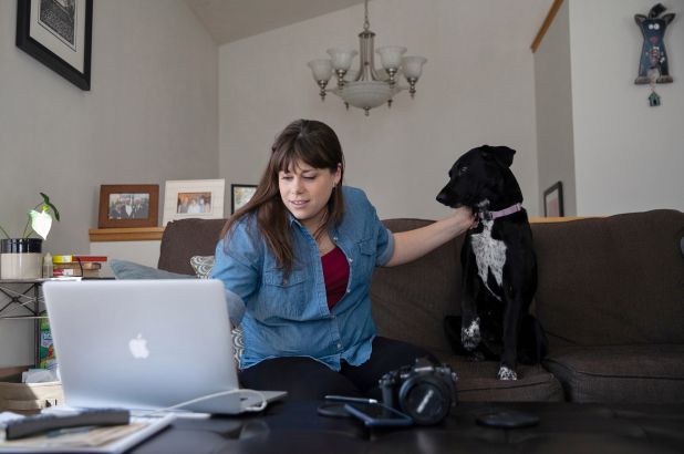 Katy McAvoy làm việc trên blog ẩm thực của cô ấy trong phòng khách với công ty của chú chó Molly của cô ấy ở Grand Rapids, Michigan 