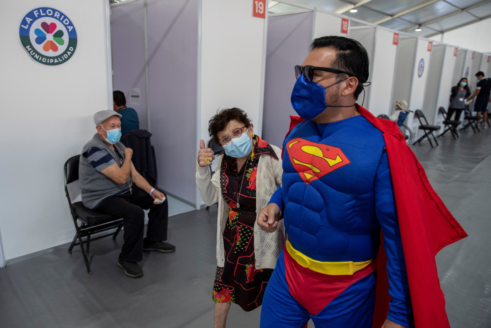 Một người đàn ông trong trang phục siêu nhân đang đưa mẹ mình đi tiêm vắc-xin COVID-19 ở thủ đô Santiago, Chile - Ảnh: 