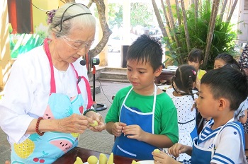 Nghệ nhân ẩm thực Mai Thị Trà hướng dẫn làm bánh cho thiếu nhi - Ảnh: Nguoilamnghe