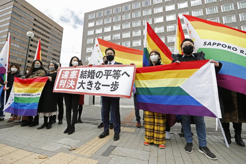 Các luật sư và những người ủng hộ nguyên đơn cầm cờ “sắc cầu vồng” và biểu ngữ có nội dung Phán quyết vi hiến bên ngoài tòa án quận Sapporo sau khi tòa ra phán quyết phán hôm 17/3 - Ảnh: AP/Kyodo News
