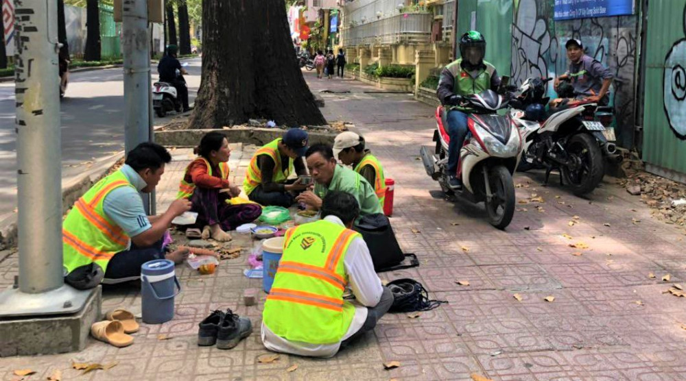 Sau những giờ làm việc vất vả, các công nhân làm cho một công trình ở góc đường Pasteur - Nguyễn Đình Chiểu tập trung trên vỉa hỉa ăn bữa cơm vội 