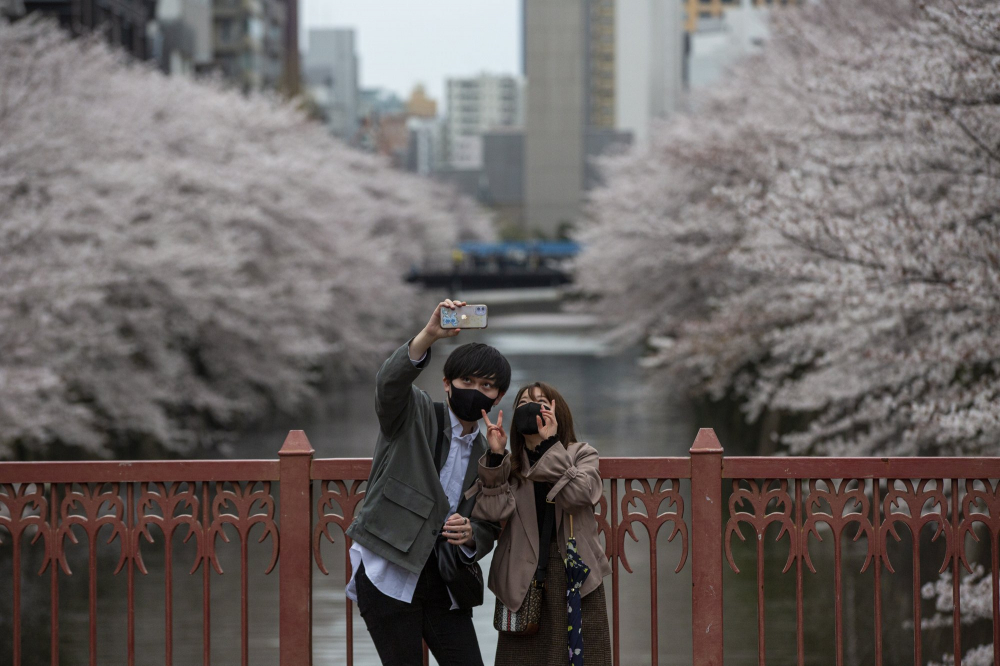 Một cặp đôi chụp ảnh tự sướng trên cây cầu bắt ngang sông Meguro khi hoa anh đào nở vào ngày 28/3