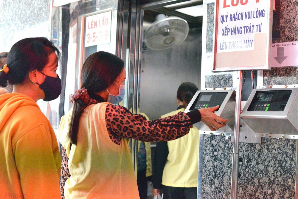 Người nuôi bệnh quét vân tay trước khi vào thang máy đi lên khu vực phòng bệnh ở Bệnh viện Chợ Rẫy - Ảnh: Hiếu Nguyễn