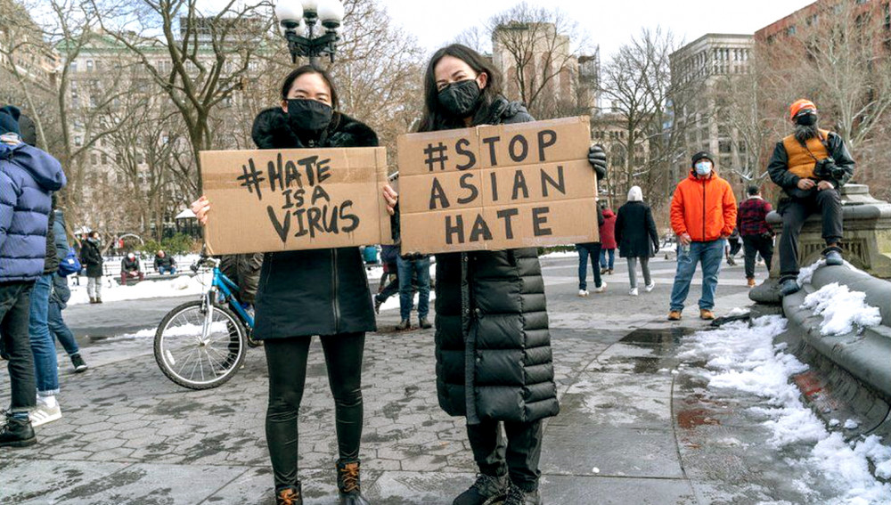 Phụ nữ châu Á cầm biển “Thù hận là một thứ vi-rút” phản đối tình trạng bạo lực chống người gốc Á ở Mỹ  - Ảnh: Getty Images