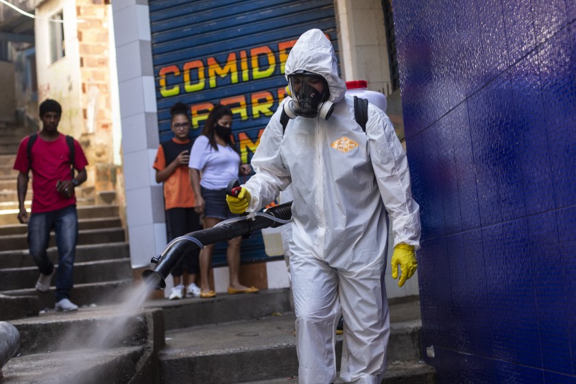 Một tình nguyện viên phun thuốc khử trùng trong một con hẻm để giúp ngăn chặn sự lây lan của coronavirus ở Rio de Janeiro - Ảnh: AP