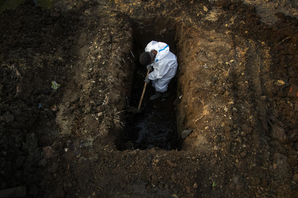 Một người đàn ông mặc đồ bảo hộ đào đất để chôn xác người chết vì COVID-19 ở Gauhati, Ấn Độ hôm 25/4