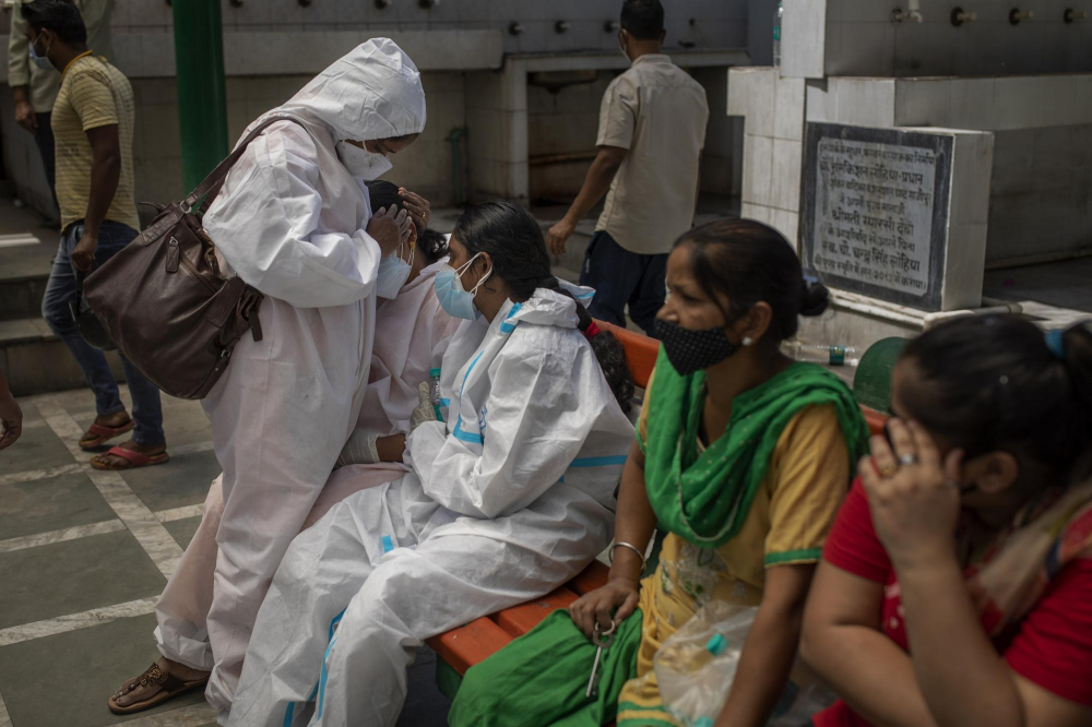 Một phụ nữ được người thân an ủi tại lò hỏa táng trong lễ hỏa táng hàng loạt nạn nhân COVID-19, ở New Delhi, Ấn Độ