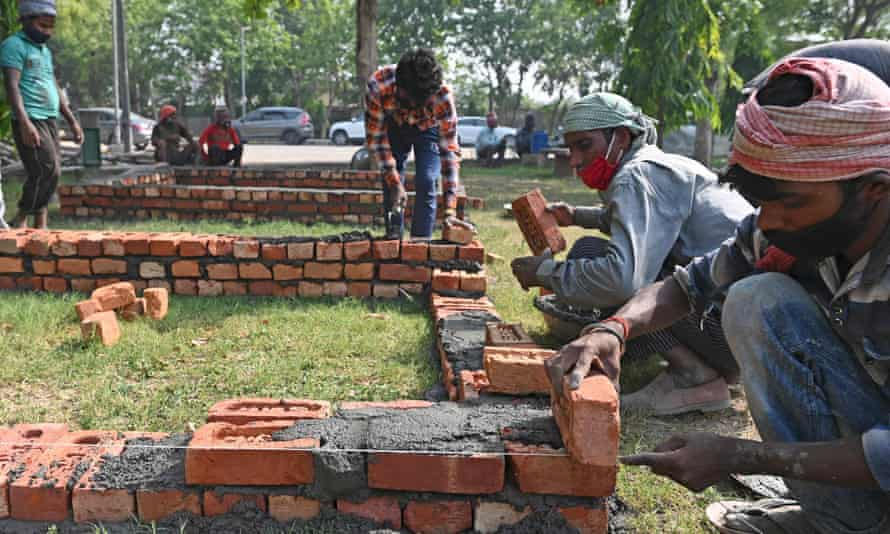 CÔng nhân đang xây dựng các bệ tạm cho giàn hỏa táng dã chiến trong một công viên bên trong khuôn viên của một lò hỏa táng ở Delhi