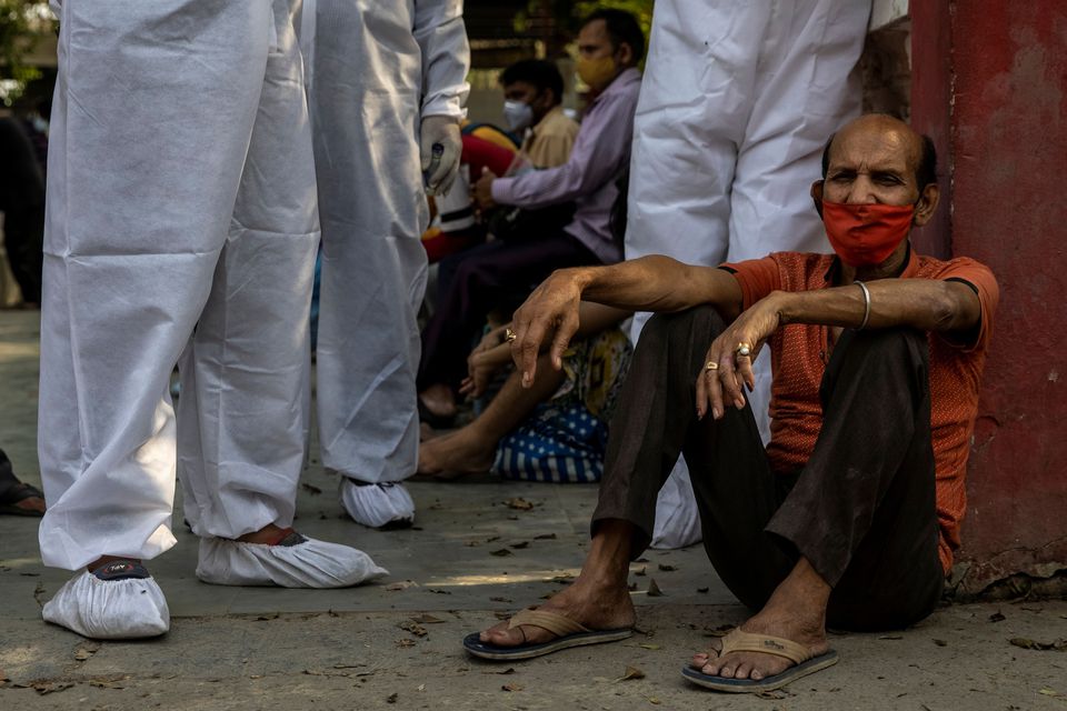 Một thân nhân ngồi chờ lượt hỏa táng thi thể người thân tại New Delhi